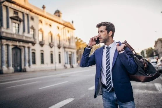 Homme en costume téléphonant avec un sac sur l’épaule.
