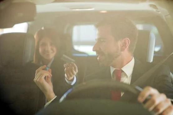 Chauffeur au volant échangeant avec une passagère assise à l’arrière.