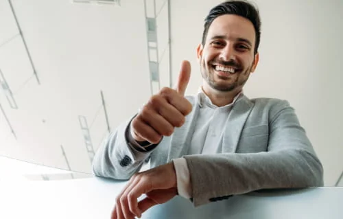 Homme souriant faisant un signe du pouce dans une voiture.